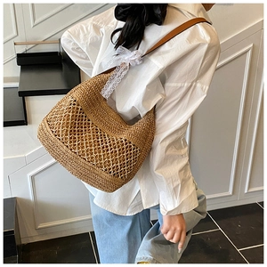 Detail of woven straw shoulder bag with hollow mesh design and lace bow decoration