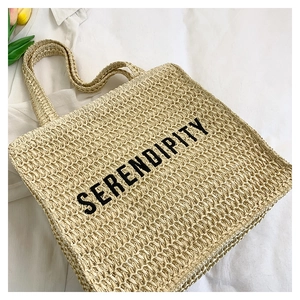 Detailed close-up of woven straw tote bag with SERENDIPITY text and tactile texture