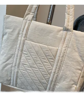 Close-up of beige quilted tote bag showing detailed twill stitching and soft fabric texture