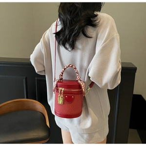 Detail of red cylindrical bucket bag with silk scarf handle and gold hardware padlock