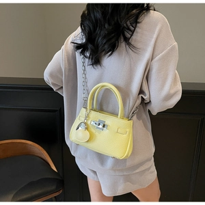 Rear view of a model carrying a bright yellow pebble leather bucket bag with silver chain strap