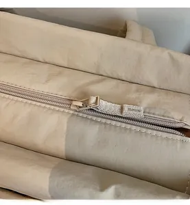 Close-up of smooth beige zipper with fabric puller on durable padded canvas tote bag