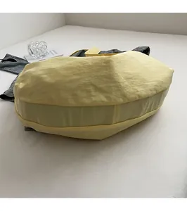 Detailansicht einer großen hellgelben Nylon-Halbmondtasche mit breitem Schultergurt