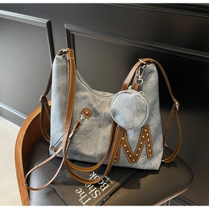 Detail of blue canvas hobo bag with brown leather strap and small round coin purse