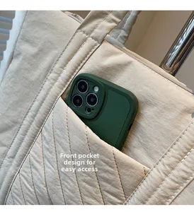 Detail of beige quilted canvas tote featuring a convenient front pocket for smartphones