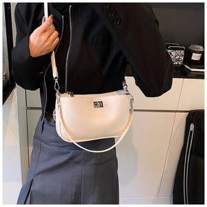Detail of beige leather crossbody bag with silver buckle worn by a model in casual outfit