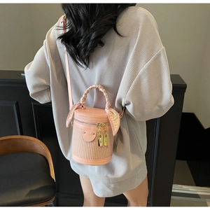 Close-up of pink cylindrical woven bucket bag with silk scarf and gold lock accents