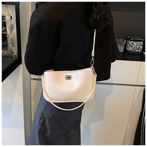 Model wearing a chic beige leather shoulder bag with a silver rotary metal clasp lock