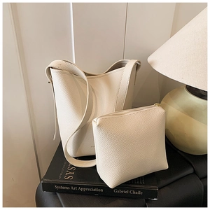 Close-up of cream-colored bucket bag and matching coin purse with lychee leather texture