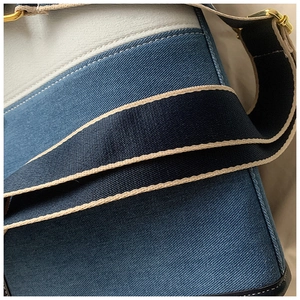 Détail du sac en denim avec bandoulière tissée large et ferrures métalliques dorées