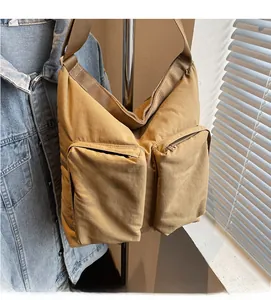 Detail of khaki nylon crossbody bag showing dual zipper pockets and wide woven strap