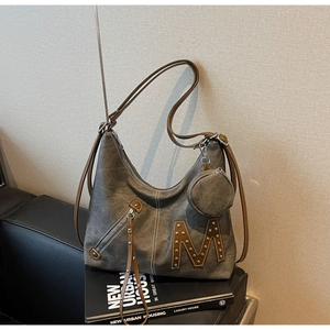Close-up of grey canvas tote featuring silver rivet M detail and hanging round coin purse
