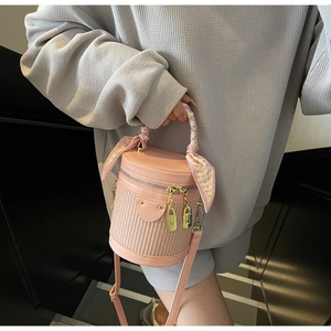 Detail view of pink woven cylinder bag with silk scarf handle and gold metallic zipper