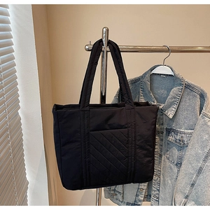 Detail of the black quilted tote bag hanging with a denim jacket in natural light