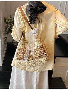 Straw shoulder bag with white lace bow and brown leather strap for beach vacation