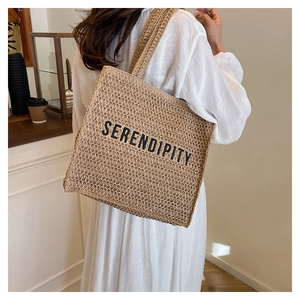 Detail shot of the woven straw tote bag texture and Serendipity lettering on the front