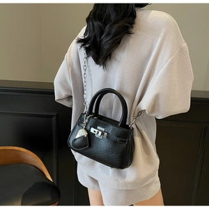 Detail of black pebbled leather bucket bag with silver turn-lock and heart charm