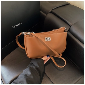 Detailed view of brown leather shoulder bag featuring silver metal lock and zip pockets