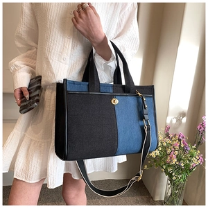 Détail d'un sac cabas en denim bicolore avec fermoir rotatif doré et anses en toile