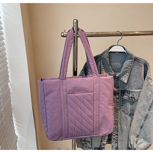 Detail of purple quilted canvas tote bag showing the textured pocket and soft padded handle