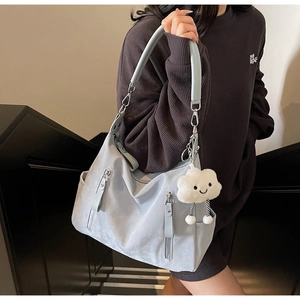 Détail du sac hobo gris-bleu avec poches zippées et breloque en peluche nuage blanc