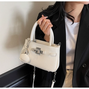 Detailed view of white lychee leather bucket bag with silver metal lock and side straps
