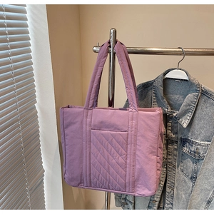 Detailed view of the purple quilted tote bag showing padded texture and side pockets