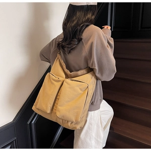 Detail of canvas tote bag with two large front utility pockets on wooden stairs