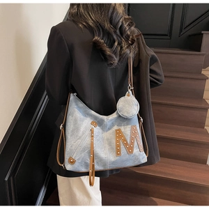 Detail of denim tote bag with leather M letter patch and mini round coin purse