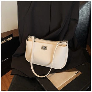 Detailed close-up of the elegant silver metal twist lock on a beige faux leather bag