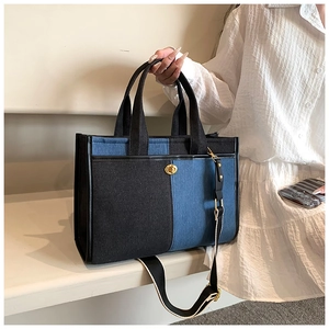 Detail view of denim and PU patchwork tote bag with gold lock and woven shoulder strap