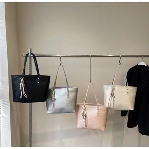 Detailed display of large tote bags in four colors with fringe charms and dual straps