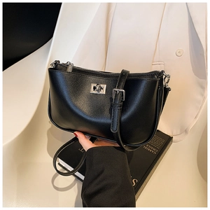 Detailed macro view of black leather crossbody bag featuring silver metal twist lock closure