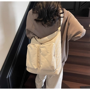 Detail of beige canvas tote bag with front utility pockets and wide shoulder strap