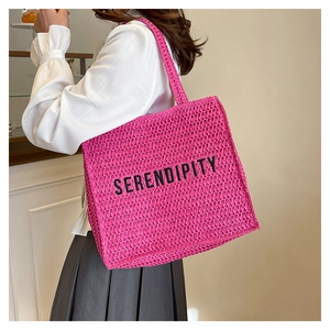 Detail of hot pink woven tote bag featuring black SERENDIPITY embroidery text