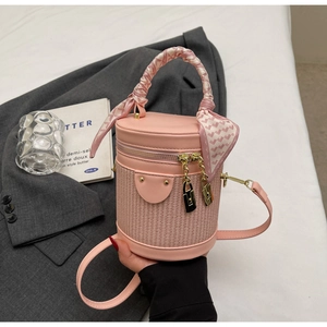 Detail of pink cylindrical bag with woven texture, silk scarf handle and gold zippers