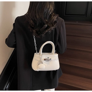 Detail of a beige pebbled leather mini bucket bag with silver hardware and chain strap
