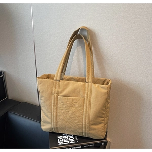 Detail of khaki tote bag showing quilted texture and convenient front pocket design