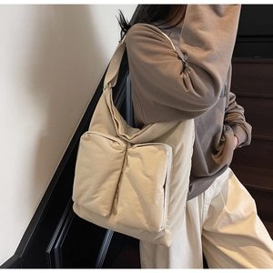 Detail shot of large canvas tote bag with front utility pockets and wide strap on model