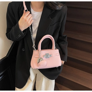 Detail of pink lychee leather bucket bag with silver heart charm and chain strap