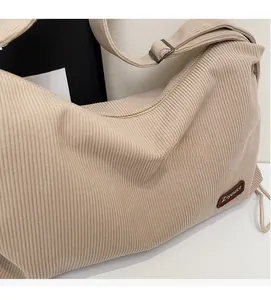 Detailed close-up of beige corduroy fabric texture and brown leather logo patch on shoulder bag