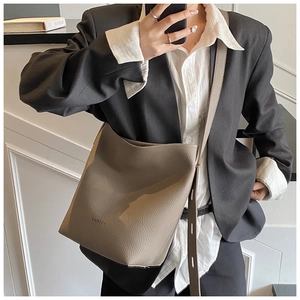 Chic taupe bucket bag with litchi grain texture worn with a professional black blazer