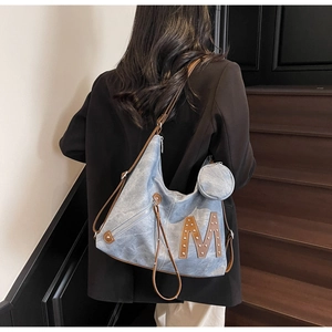 Detail of blue denim hobo bag with brown leather M patch and mini round coin purse