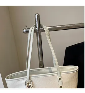 Detail of cream white leather tote bag with sturdy handles and silver ring hardware