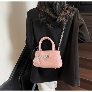 Detail of pink lychee leather bucket bag with silver chain strap and heart charm