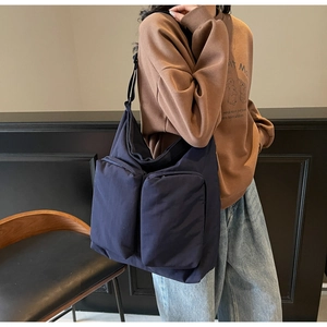 Detail view of a navy blue large capacity nylon shoulder bag with functional dual zip pockets