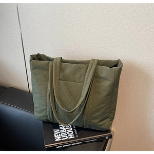 Detail of olive green quilted tote bag with diagonal stitching on a sleek black sofa