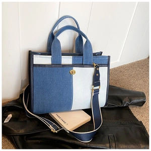Détail du sac cabas en denim bicolore avec fermoir rotatif doré et bandoulière large