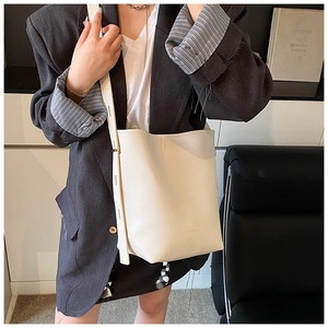Close-up of cream pebble leather bucket bag showing grain texture and brand logo detail