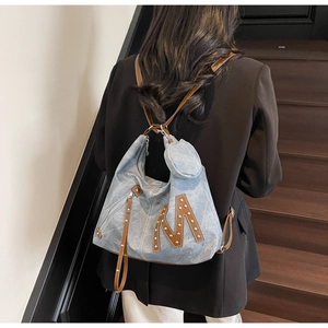 Detail of light blue tote bag with metallic stud M logo and mini round coin purse